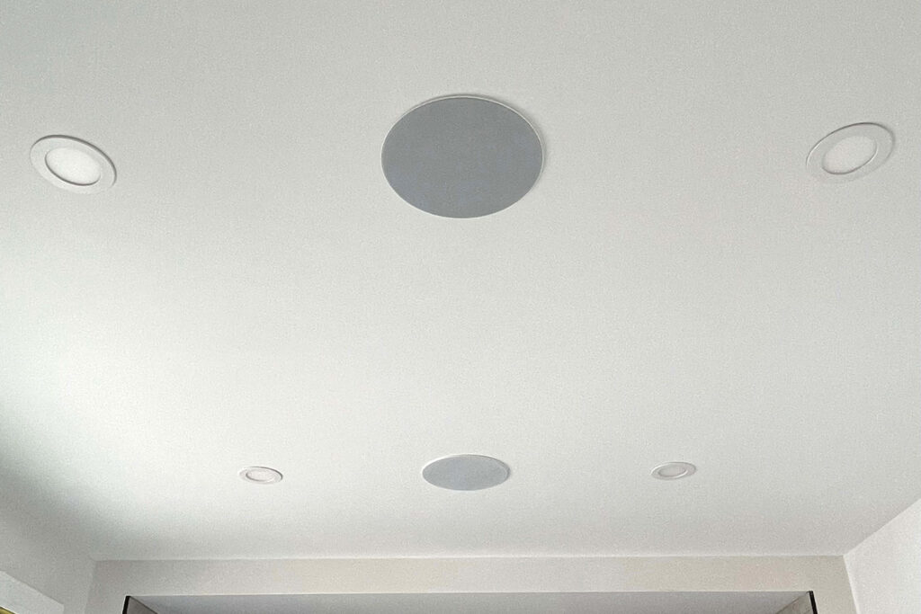 In-ceiling speakers and pot lights on a white ceiling