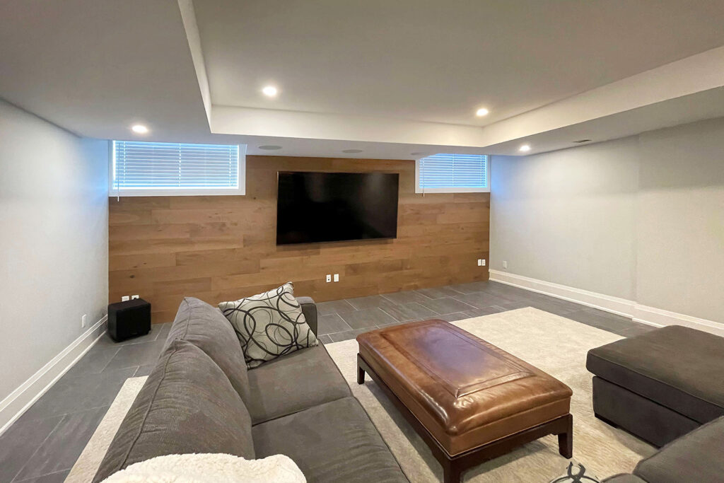 an entertainment room in a basement has a big tv installed on the wall