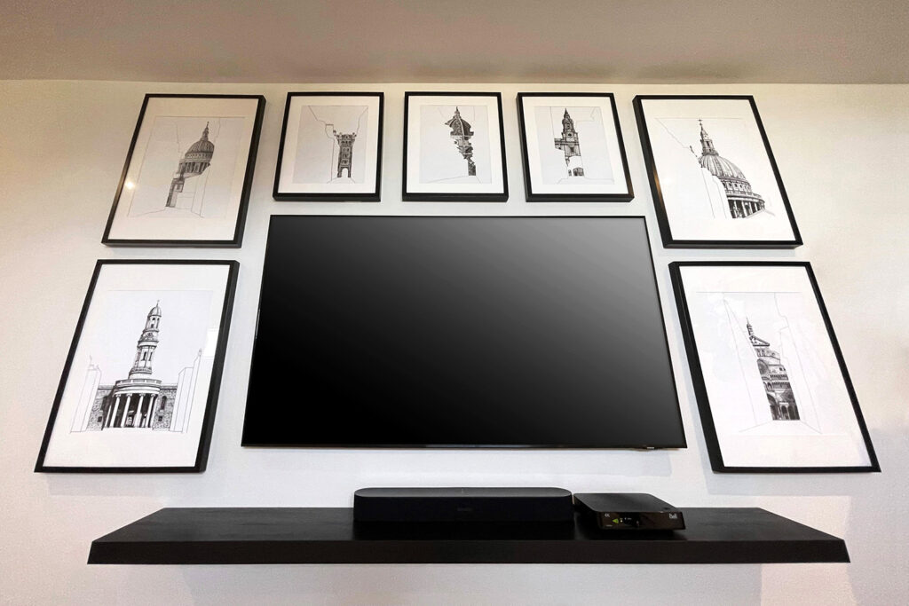 A TV and frames on a wall with a TV setup box