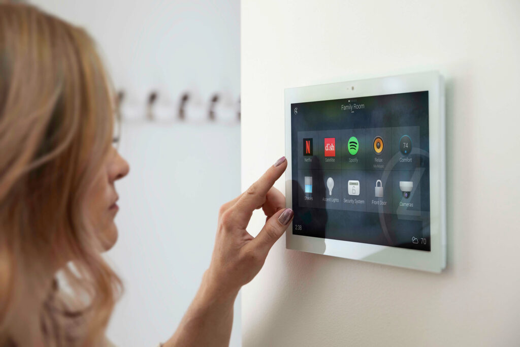 A female is trying to operate a smart home application on a pad that is installed on a wall.
